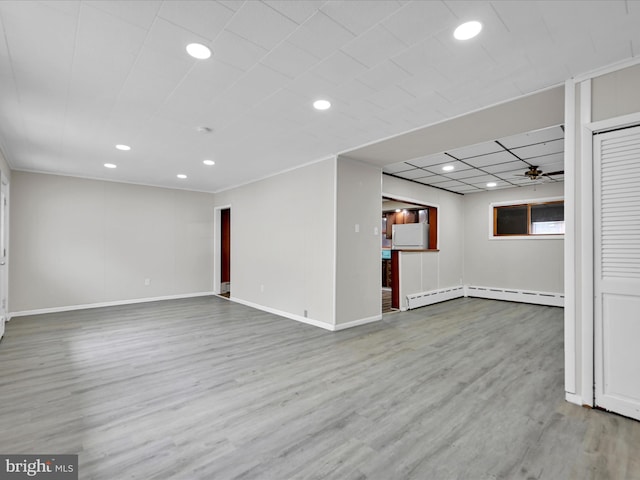 below grade area with baseboard heating, baseboards, wood finished floors, and recessed lighting
