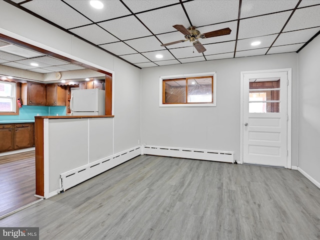 unfurnished room with a baseboard radiator, a drop ceiling, wood finished floors, and ceiling fan