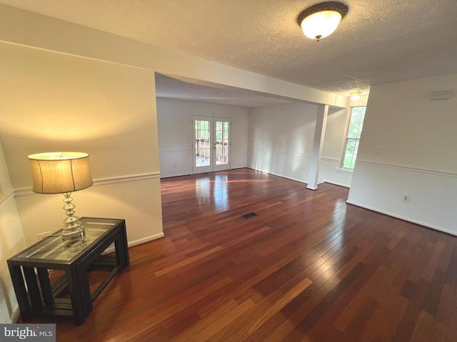 unfurnished room featuring baseboards, visible vents, a textured ceiling, and wood-type flooring