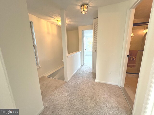 corridor with carpet floors and an upstairs landing