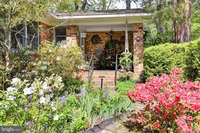 property entrance with brick siding and a porch