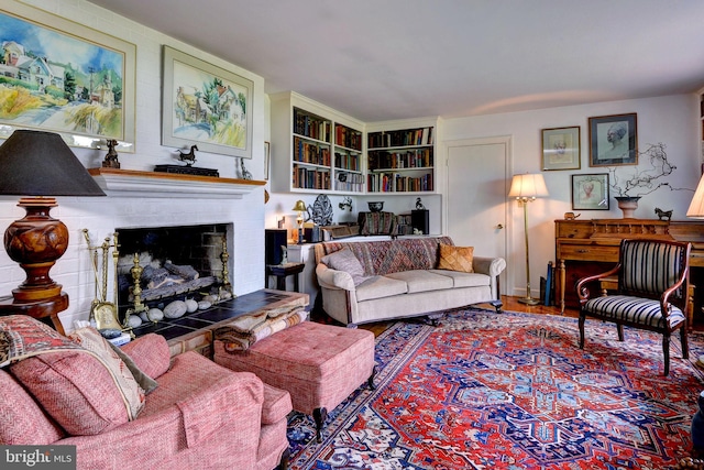 living room with wood finished floors and a fireplace with raised hearth