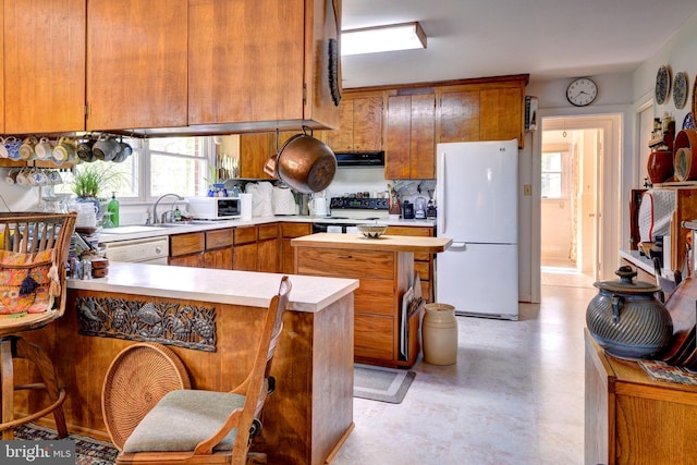 kitchen featuring plenty of natural light, light countertops, white appliances, and a peninsula
