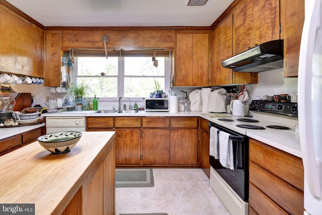 kitchen featuring brown cabinets, a sink, under cabinet range hood, and white appliances