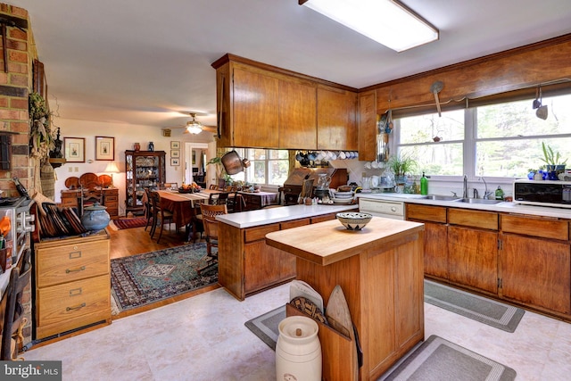 kitchen featuring brown cabinetry, a sink, butcher block countertops, and a healthy amount of sunlight