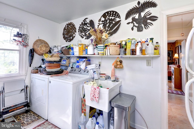 laundry room featuring a healthy amount of sunlight, washing machine and clothes dryer, a sink, and laundry area