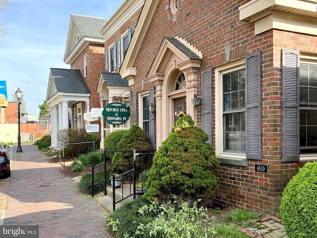 view of property exterior featuring fence and brick siding