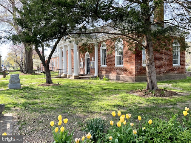 view of front of house with a front lawn, brick siding, and a chimney