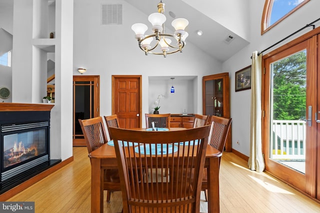 30602 Sandy Landing Rd, Dagsboro, DE 19939 - dining room featuring visible vents, high vaulted ceiling, a glass covered fireplace, light wood finished floors, and an inviting chandelier