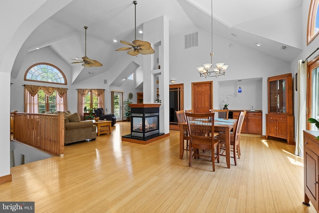 30602 Sandy Landing Rd, Dagsboro, DE 19939 - dining space with light wood finished floors, high vaulted ceiling, ceiling fan with notable chandelier, a multi sided fireplace, and visible vents