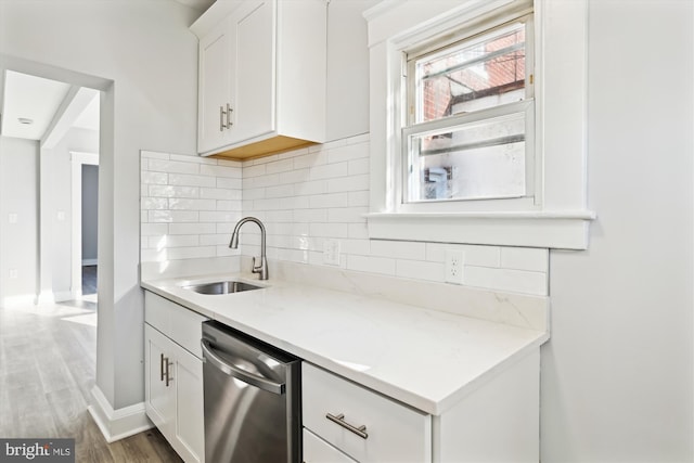 kitchen with tasteful backsplash, white cabinets, a sink, dishwasher, and wood finished floors