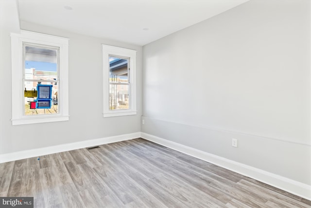 empty room featuring baseboards, visible vents, and wood finished floors