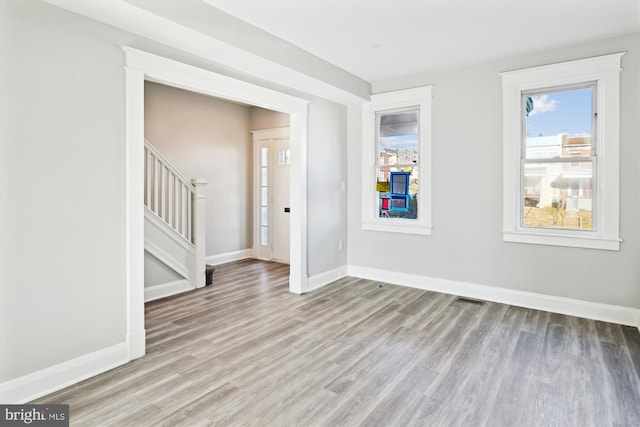 foyer with baseboards, wood finished floors, and stairs