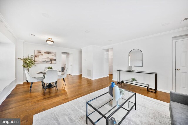 living room featuring wood finished floors, visible vents, crown molding, and baseboards