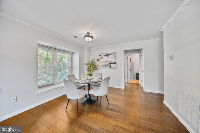 dining space featuring wood finished floors, visible vents, and ornamental molding
