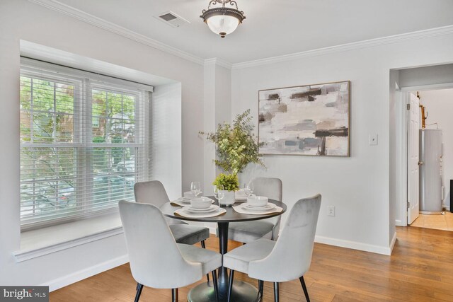 dining area with baseboards, wood finished floors, visible vents, and crown molding
