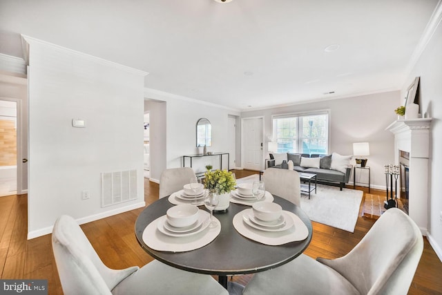 dining area with wood finished floors, visible vents, baseboards, and ornamental molding