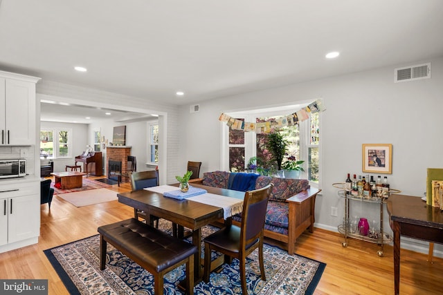 dining room featuring recessed lighting, a brick fireplace, light wood-style flooring, and visible vents