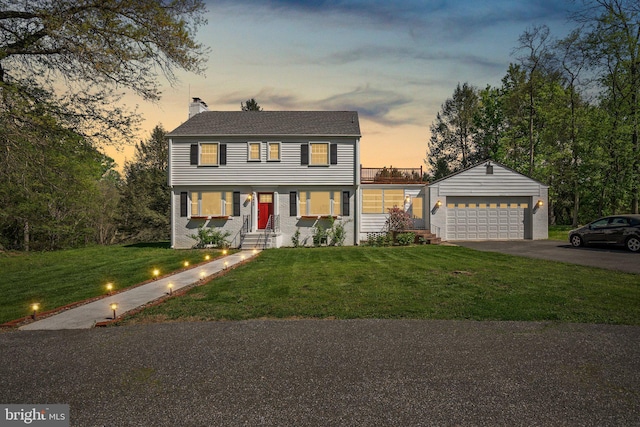 colonial inspired home featuring a chimney, a yard, and a detached garage