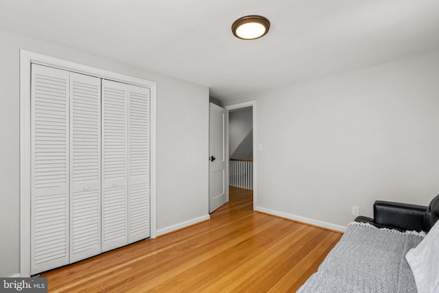 bedroom with baseboards, light wood-style floors, and a closet