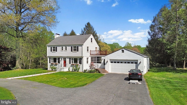 colonial inspired home with roof with shingles, a front lawn, driveway, a chimney, and a garage