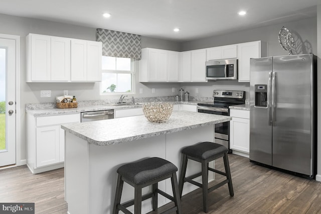 kitchen with appliances with stainless steel finishes, a sink, white cabinetry, and a kitchen breakfast bar