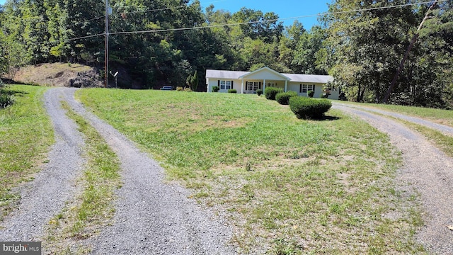 single story home featuring gravel driveway and a front lawn