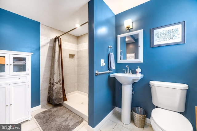 full bathroom with toilet, a tile shower, and tile patterned flooring