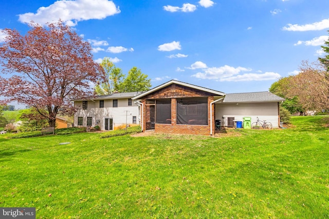 rear view of property featuring a yard, brick siding, and a sunroom