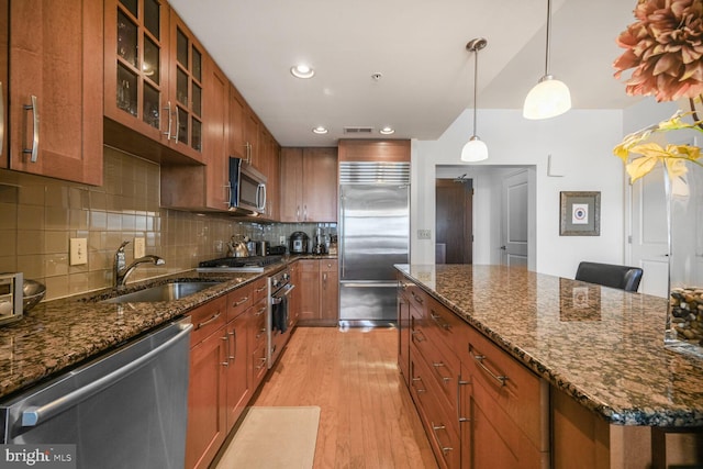 12500 Park Potomac Ave Unit 905South, Potomac, MD 20854 - kitchen featuring stainless steel appliances, a sink, brown cabinets, light wood finished floors, and glass insert cabinets