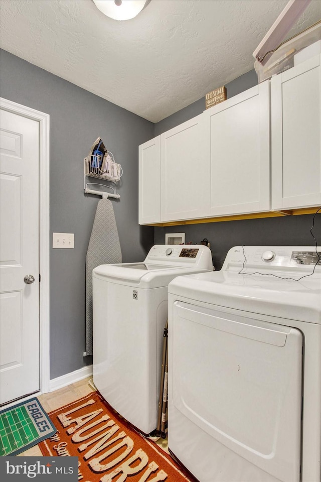laundry room with separate washer and dryer, baseboards, a textured ceiling, and cabinet space