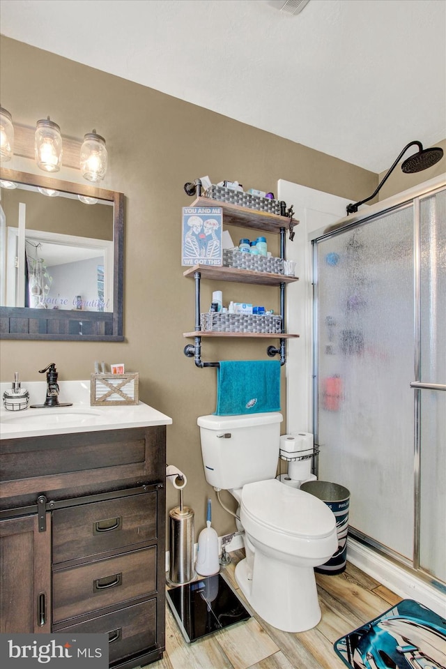 full bath with vanity, wood finished floors, a shower stall, and toilet