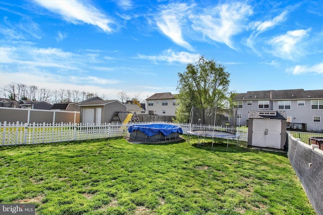 view of yard featuring a fenced backyard, a residential view, an outdoor structure, a storage unit, and a trampoline