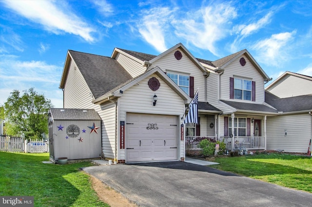 view of front facade with a front lawn, covered porch, fence, a garage, and aphalt driveway