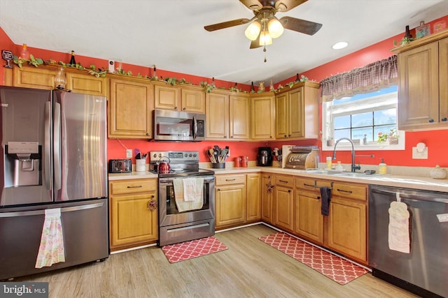 kitchen featuring light countertops, a ceiling fan, a sink, light wood-style floors, and appliances with stainless steel finishes