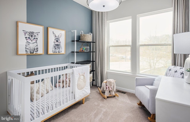 carpeted bedroom featuring baseboards, visible vents, and a crib