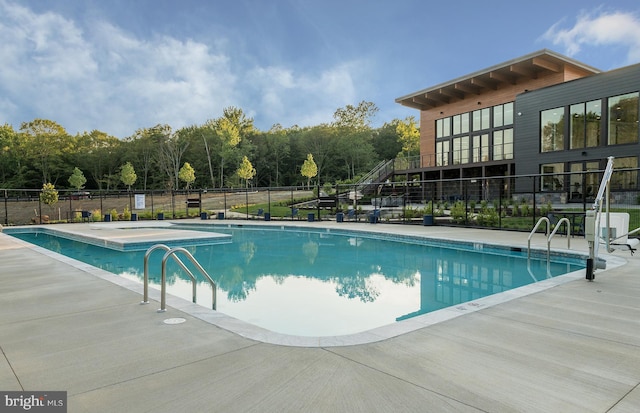 community pool with a patio area and fence