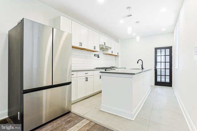 kitchen featuring tasteful backsplash, stainless steel appliances, under cabinet range hood, a sink, and visible vents