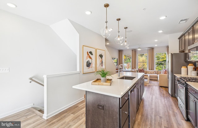 kitchen featuring dark brown cabinetry, appliances with stainless steel finishes, a sink, and light wood-style floors