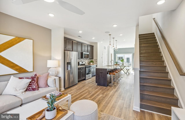 living room featuring light wood-type flooring, visible vents, recessed lighting, and stairway