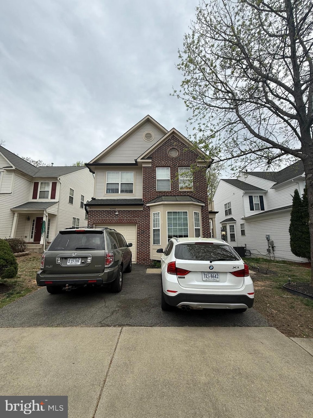view of front facade with an attached garage, driveway, and brick siding