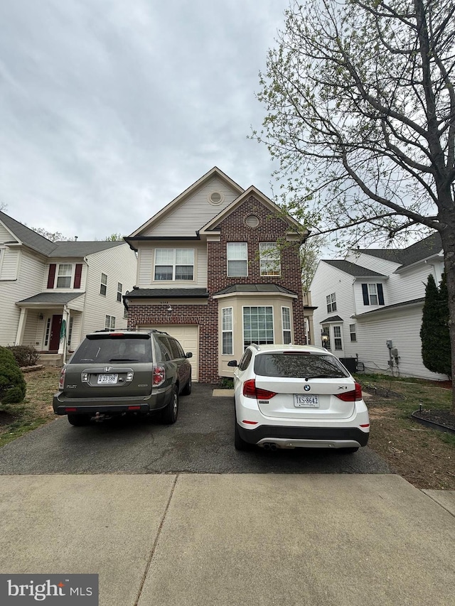 view of front facade with an attached garage, driveway, and brick siding