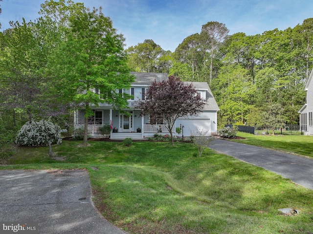 view of front facade featuring a garage, covered porch, a front yard, and aphalt driveway