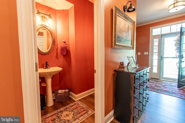 bathroom with crown molding, baseboards, wood finished floors, and a sink