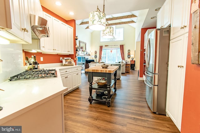 kitchen with open floor plan, wood finished floors, wall chimney range hood, and stainless steel appliances