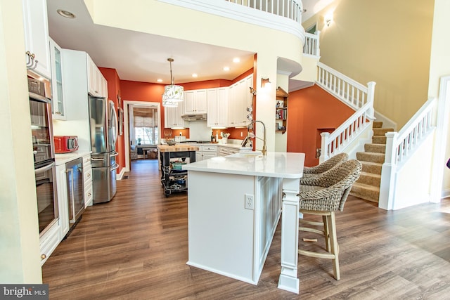 kitchen with appliances with stainless steel finishes, a sink, dark wood finished floors, wine cooler, and glass insert cabinets