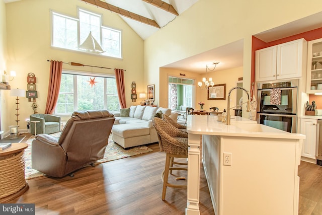kitchen with high vaulted ceiling, open floor plan, an inviting chandelier, and double oven