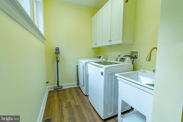 clothes washing area with wood finished floors, baseboards, cabinet space, and washer and clothes dryer