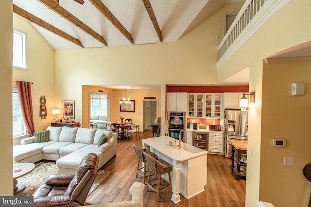 living room featuring an inviting chandelier, high vaulted ceiling, beverage cooler, and wood finished floors