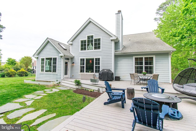 rear view of property with roof with shingles, a wooden deck, a chimney, and a yard